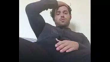 Tatuado em roupa social se divertindo sozinho em seu sofá